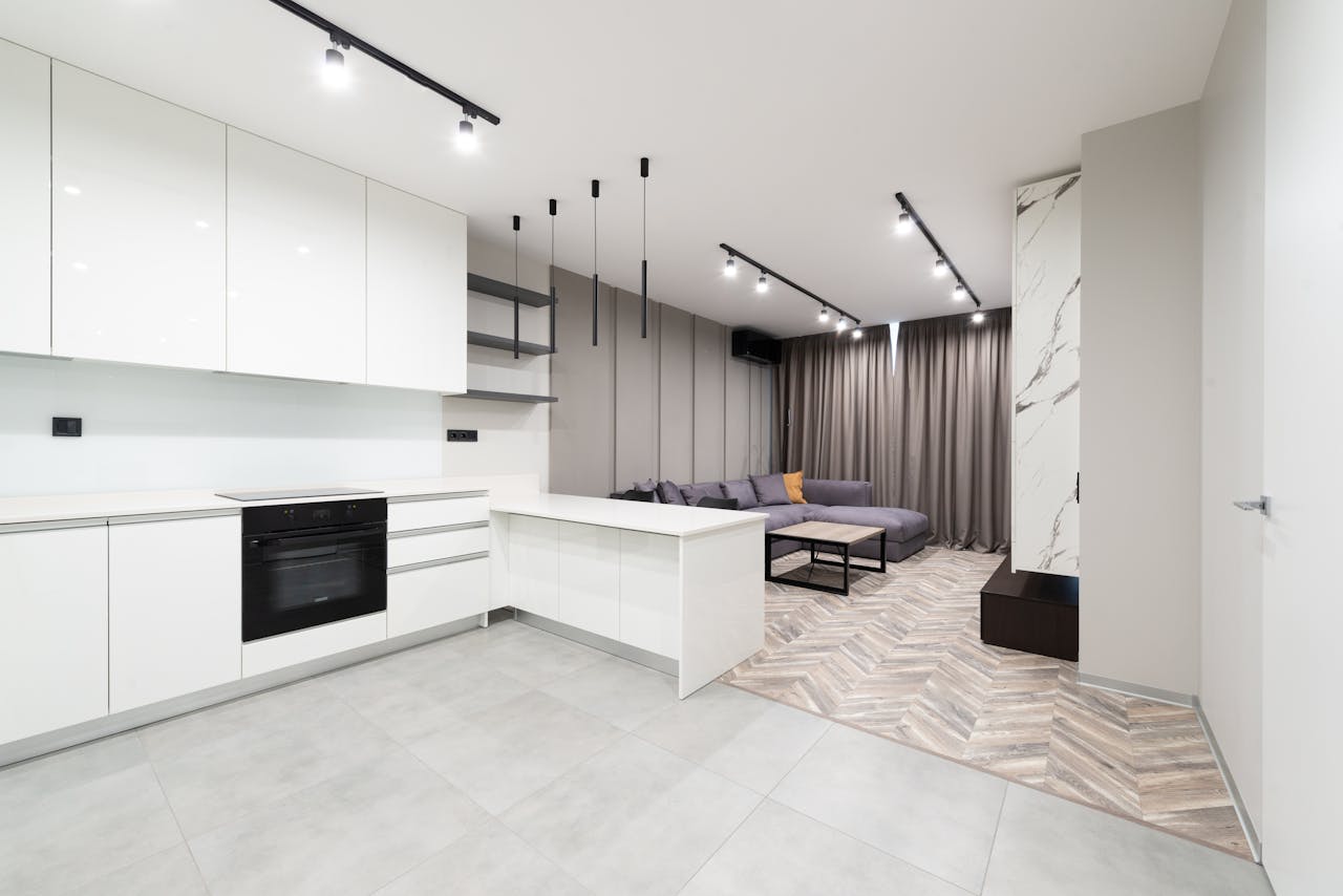 Sleek open-plan kitchen and living area with contemporary design featuring white cabinets and neutral tones.